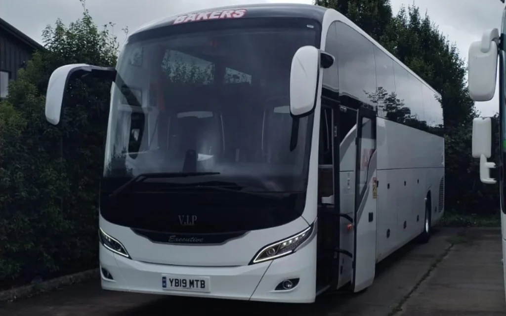 The front exterior of the YUTONG T122HDH coach in white, with tinted windows and an open side door, displaying its sleek VIP Executive design.